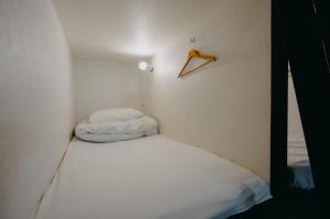东京unito light SHIMBASHI的小房间设有一张床和墙上的衣架