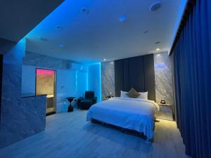 Mingjian沐野汽车旅馆 的一间卧室配有一张蓝色灯光的大床