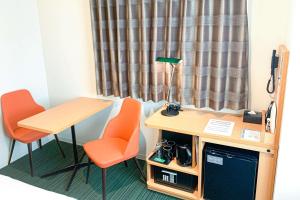 松山Comfort Hotel Matsuyama的客房设有书桌、两把椅子和一张桌子