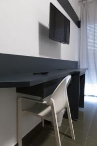 阿韦尔萨Hotel del Sole-Aversa的一张带白色椅子的黑色书桌和一台电视机