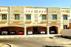 艾恩Full Apartment in Central Al Ain (All Amenities)的一座大型建筑,前面有汽车停放