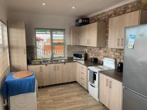 StrandfonteinStrandfontein holiday house的厨房配有木制橱柜和白色冰箱。