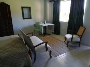 戈登湾Crossroads Guestrooms的一间卧室配有一张床、两把椅子和一张桌子