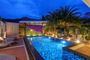 Ban Khlong Haeng3 Bedroom Platinum Pool Villa Smooth as Silk的棕榈树和灯光的夜间游泳池