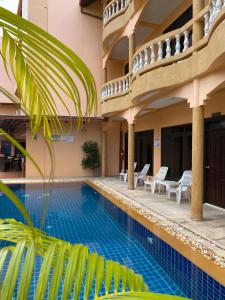 芭东海滩Baan Sudarat Hotel的一座带椅子的酒店游泳池以及一座建筑