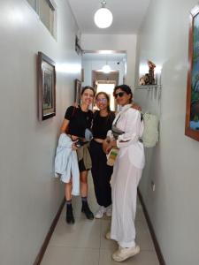 伊基托斯100 RV Apartments Iquitos-Apartamento primer piso con vista a piscina的三个女人站在走廊上,摆着一张照片