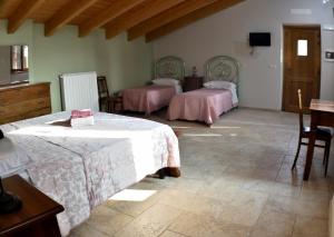 Ozzano Monferratob&b CASCINA SORTINA Country House的一间卧室配有两张床和一张桌子及椅子