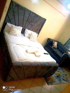 内罗毕Attic place South B.的一间卧室配有一张带床头板和椅子的床