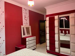 丹吉尔Appartement Tanger的一间卧室设有红色的墙壁、一张床和镜子