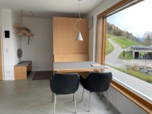 施瓦岑贝格Bregenzerwaldblick的厨房配有书桌、两把椅子和窗户。