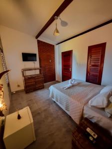 马拉戈日Aloha Beach Guest House的卧室配有白色的床和电视。