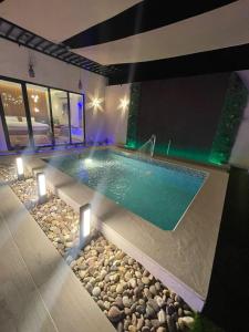 哈萨شاليه ريفو Revo chalet的一座带灯光和岩石的别墅内的游泳池