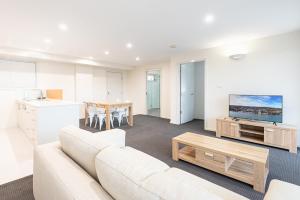 华纳海湾Warners Bay Apartments的客厅配有白色的沙发和桌子