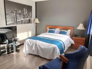 邓肯Duncan Motel的一间卧室配有一张床、一台电视和一张蓝色椅子