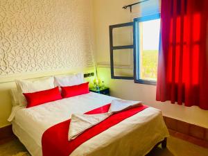 Nkob卡斯巴恩那海尔旅馆的一间卧室配有一张带红色枕头的床和一扇窗户