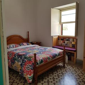 拉拉古纳Ratones de Biblioteca的一间卧室配有一张带五颜六色的被子的床和窗户