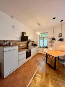 莱比锡FirstClass 2R_Apartment in Leipzig的厨房配有白色橱柜和一张铺有木地板的桌子。