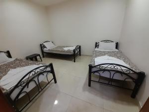 亚喀巴Farah Plaza Hostel &Hotel Apartments的一间设有三张床和椅子的房间