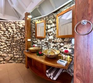 维拉港Coco Beach Resort的石头浴室设有木台和两个篮子
