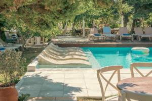阿默达拉-伊拉克利翁Georgia's Garden by Omilos Hotels的一个带椅子和桌子的游泳池以及树木
