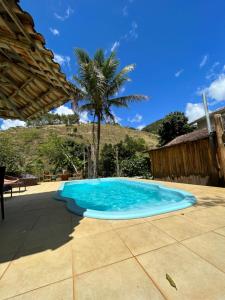 萨纳Peniel do Sana Guest House的棕榈树庭院中的蓝色游泳池