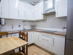 马德里NALÓN INN的厨房配有白色橱柜和木桌