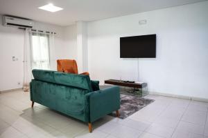 阿比让Sublime appartement à Cocody Riviera Bonoumin .的客厅配有绿色沙发和电视