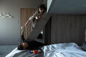 鹿儿岛FAV HOTEL KAGOSHIMACHUO的一个人躺在有楼梯的床上