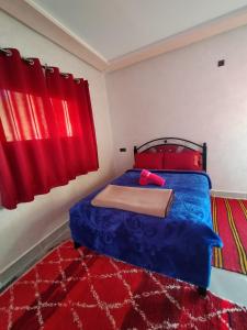 廷吉尔auberge restaurant tizgui的一间卧室配有蓝色的床和红色窗帘