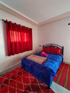 廷吉尔auberge restaurant tizgui的一间卧室配有一张蓝色的床和红色窗帘