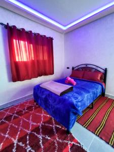 廷吉尔auberge restaurant tizgui的一间卧室配有蓝色的床和红色窗帘