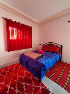 廷吉尔auberge restaurant tizgui的一间卧室设有一张床和一个红色的窗户