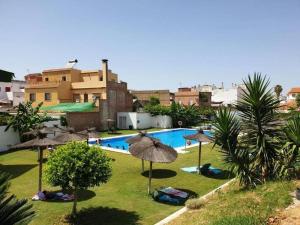 拉阿尔加瓦Alojamiento con piscina y parking en Sevilla的一个带遮阳伞的游泳池,人们躺在草地上