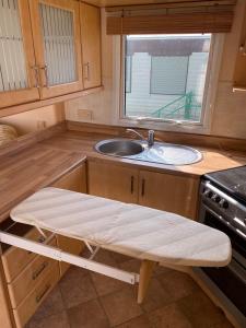 斯凯格内斯Summerlands, Ingoldmells 8 berth caravan的厨房配有水槽和长凳