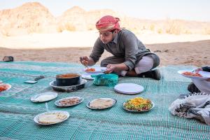 瓦迪拉姆Wadi Rum Magic Nature Camp的坐在餐桌上吃盘子的人