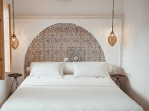 马拉喀什Riad Le Petit Joyau的一间卧室配有一张大白色床和华丽的床头板