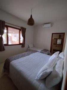 托兰克索Casa Harmonia, com 5 suítes em Trancoso-BA的卧室配有带枕头的床铺和窗户。