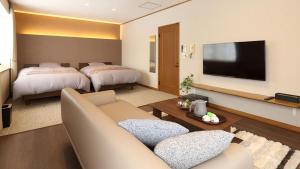 八幡平市Pension Hinode的客厅配有两张床、一张沙发和一台电视