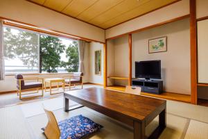 ItakoKAMENOI HOTEL Itako的客厅配有木桌和电视。