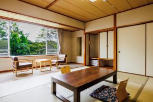 ItakoKAMENOI HOTEL Itako的客厅配有桌椅和大窗户