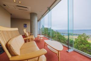 ItakoKAMENOI HOTEL Itako的一间带椅子和桌子的房间以及大窗户