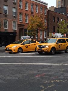 纽约Incentra Village Hotel的停在城市街道上的两辆黄色出租车