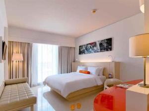 登巴萨登巴萨哈里斯酒店的配有一张床和一张书桌的酒店客房
