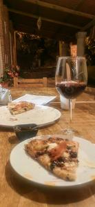 瓦斯卡坎波CABAÑAS LOS LAURELES的一张桌子,上面放着一片比萨饼和一杯葡萄酒
