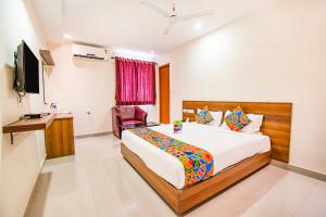 哥印拜陀FabHotel Thejas Paaradise Coimbatore International Airport的一间卧室配有一张床、一张书桌和一台电视