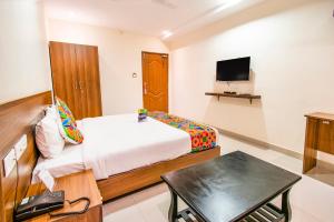 哥印拜陀FabHotel Thejas Paaradise Coimbatore International Airport的一间卧室配有一张床、一张书桌和一台电视。