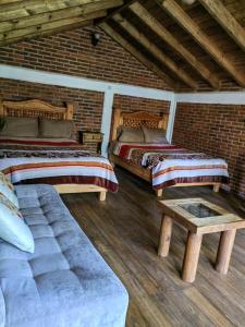 瓦斯卡坎波CABAÑAS LOS LAURELES的一间设有两张床、一张长凳和砖墙的房间