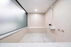 釜山Ytt酒店的白色的浴室设有浴缸和淋浴。