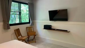 沙美岛Island House Rentals 25的卧室设有壁挂式电视和两把椅子