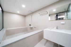 釜山Ytt酒店的白色的浴室设有浴缸和水槽。